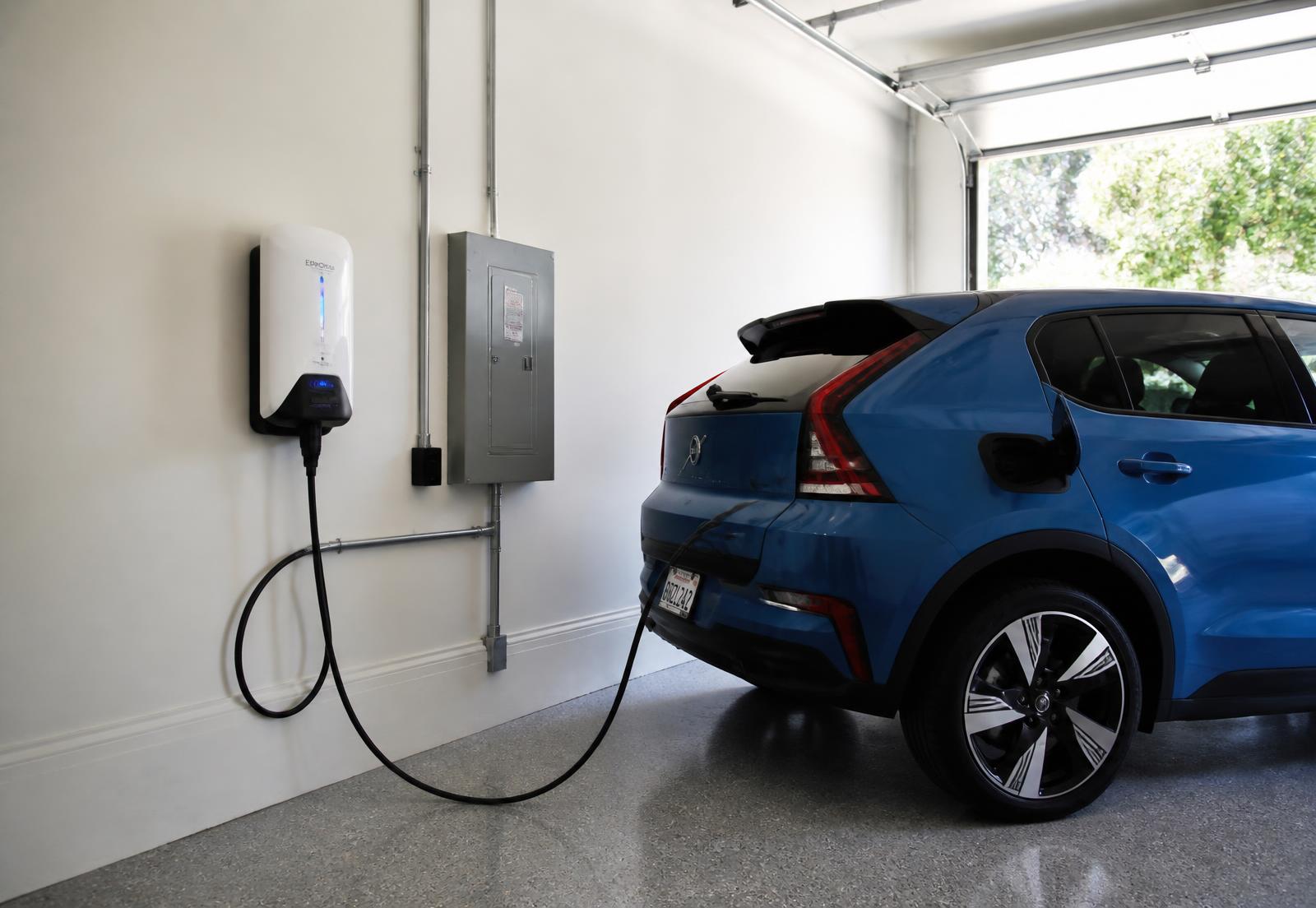 Cargador de pared para auto eléctrico instalado en la cochera de una casa con auto conectado